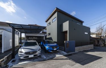 モスグリーンの外観に木目の玄関ドアが相性抜群