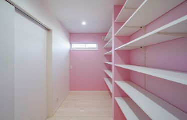 ピンク×パールホワイトのクロスで可愛らしくデザインされた奥様のプライベートルーム。趣味のアイテムを飾る、こだわりの収納棚がポイント。