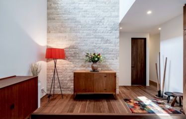 玄関正面のアクセントには天然石を敷き詰め、ダウンライトで陰影が際立つ印象に。高天井には無垢材の板張りを施し、あたたかみある仕上がりに。