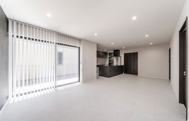 石目調のフロアタイルとバーチカルブラインドを採用し、上品に統一されたリビング。ブラックのキッチンが引き締まったアクセントに。