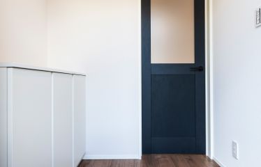 白を基調にした玄関を、ネイビーのドアがセンスよく引き締めます。フロストガラスがやわらかな光を通し、抜け感とあたたかみをプラス。