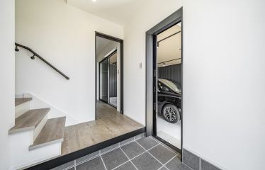 玄関から直接ガレージへのアクセスが可能で、雨の日でも濡れずに移動できます。建具や備品に合わせて、玄関のかまちも黒で統一。こだわりの空間デザインです。