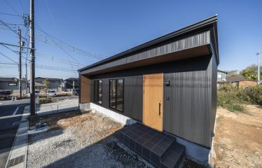 ブラックのガルバリウムに、側面までつながるレッドシダーの軒天がアクセント。