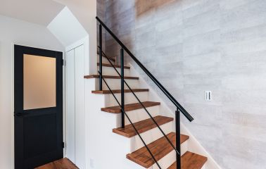 吹き抜けとオープン階段が描く、立体的で開放的な空間。 コンクリート調のクロスが、無骨すぎないインダストリアルな雰囲気を演出します。