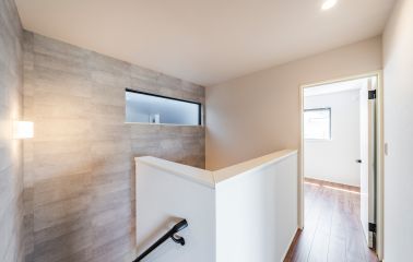 1階のコンクリート調アクセントクロスは、吹き抜けを通して天井まで貼り上げました。2階からの眺めにもこだわり、空間に縦のつながりと広がりをもたらしています。