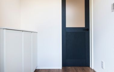 白を基調にした玄関を、ネイビーのドアがセンスよく引き締めます。フロストガラスがやわらかな光を通し、抜け感とあたたかみをプラス。